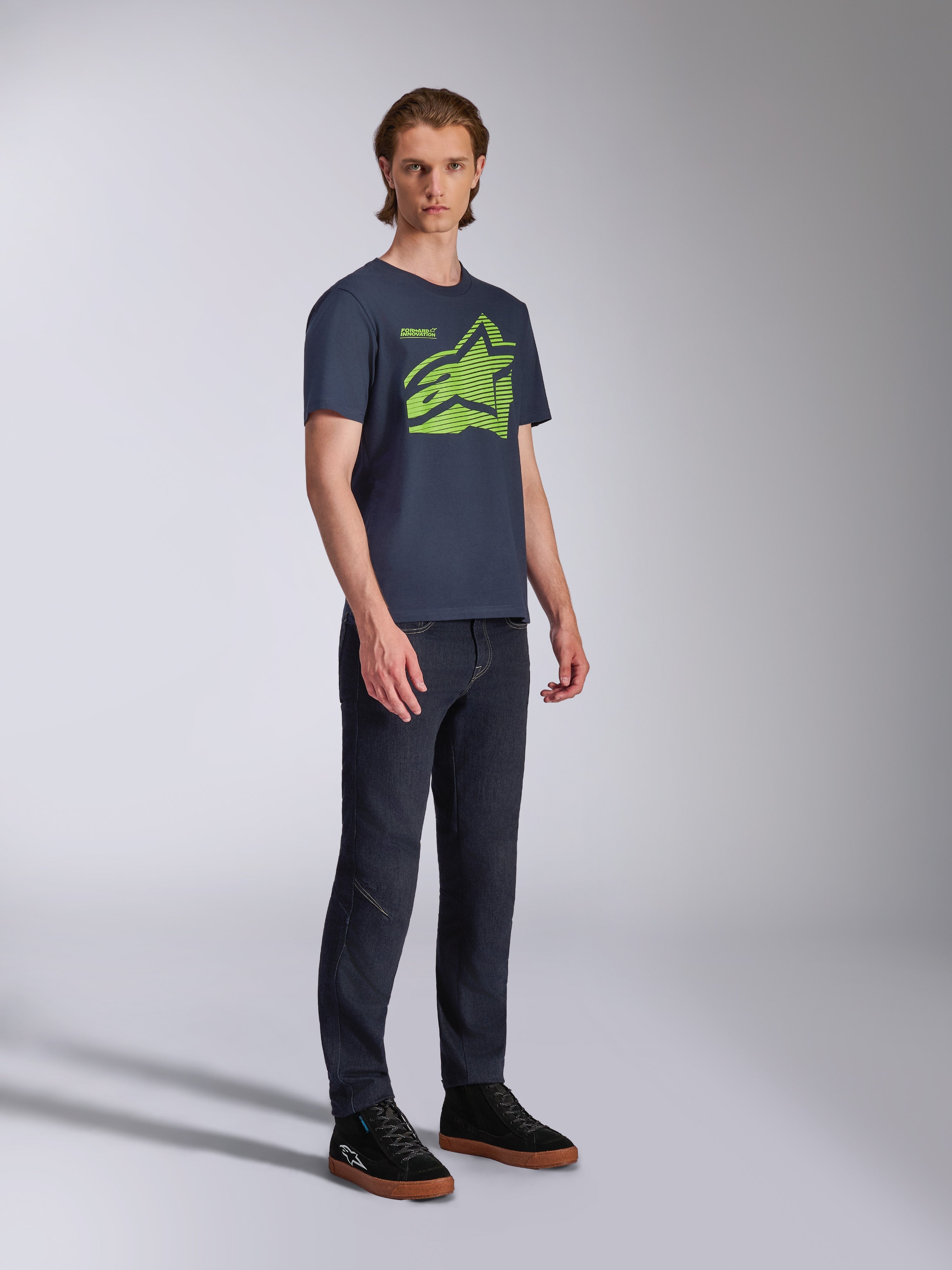 Alpinestars Fasting CSF Tee, t-shirt a maniche corte, blu navy, logo Astars geometrico verde lime, indossata con jeans scuri e sneakers nere, streetwear casual ispirato al motorsport