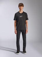 Alpinestars Frontal CSF Tee, maglietta a maniche corte, nera, logo Alpinestars bianco sul petto, indossata da un modello con pantaloni neri e scarpe nere, abbigliamento sportivo casual ad alte prestazioni