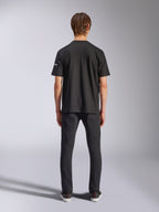 Alpinestars Frontal CSF Tee, maglietta a maniche corte, nero, vista posteriore su modello che indossa jeans neri, streetwear casual ad alte prestazioni con dettaglio del piccolo logo bianco sulla manica