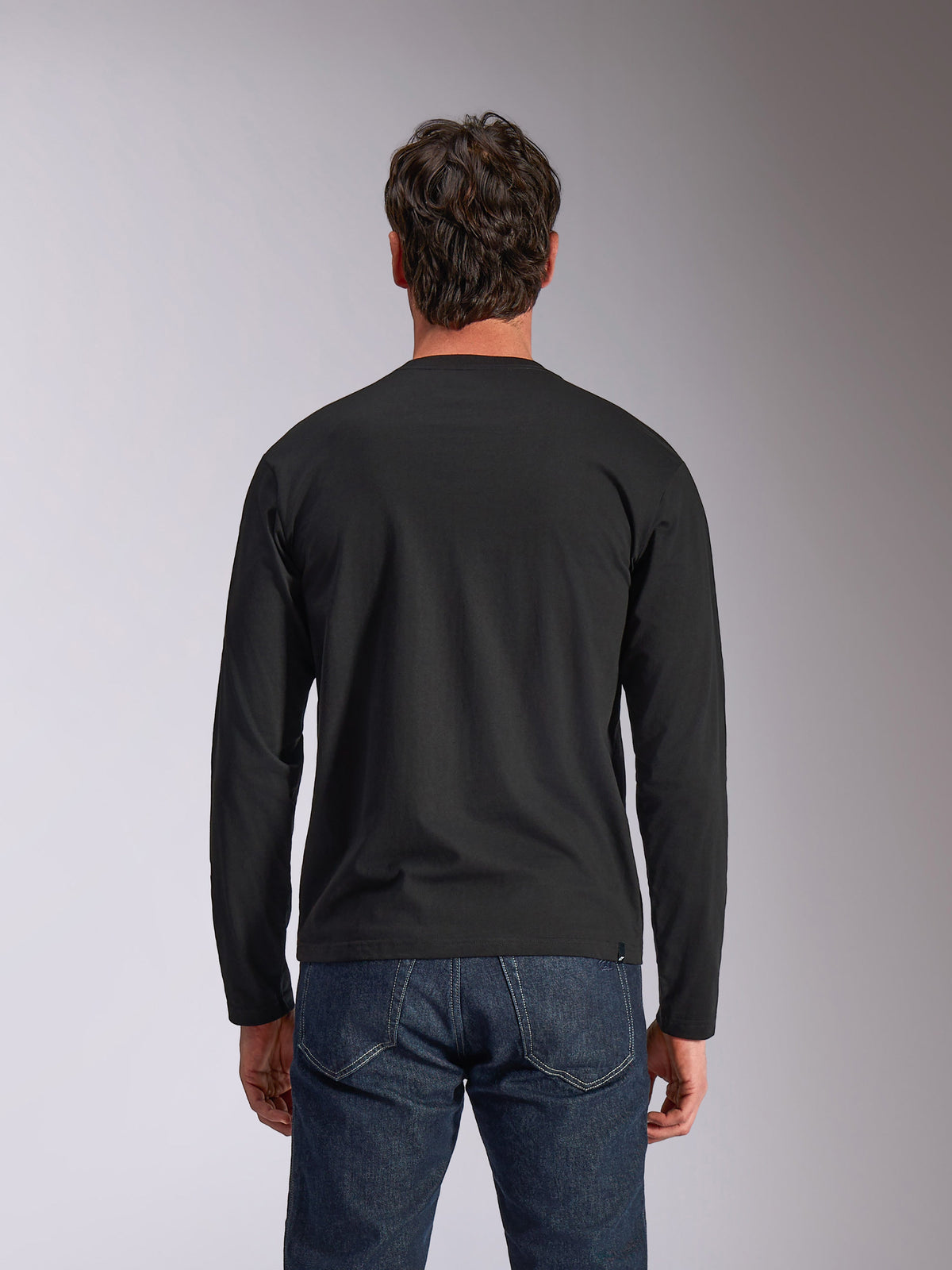 Alpinestars Trackside CSF Tee, maglia a maniche lunghe, nera, vista posteriore, indossata con jeans in denim blu scuro, streetwear casual ispirato al motorsport