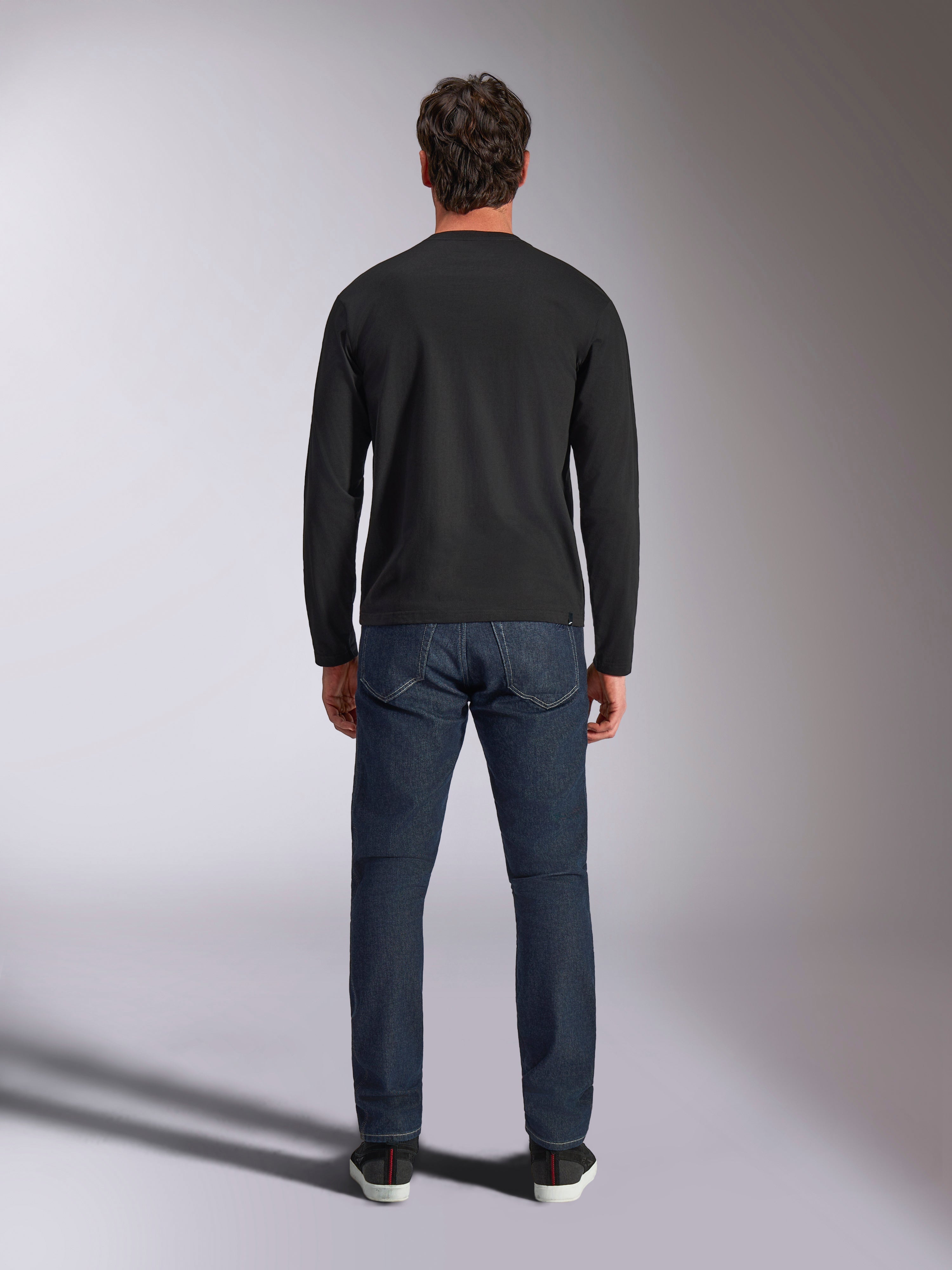 Alpinestars Trackside CSF Tee, maglia a maniche lunghe, nero, vista posteriore su un modello che indossa jeans in denim blu scuro, streetwear casual ispirato al motorsport