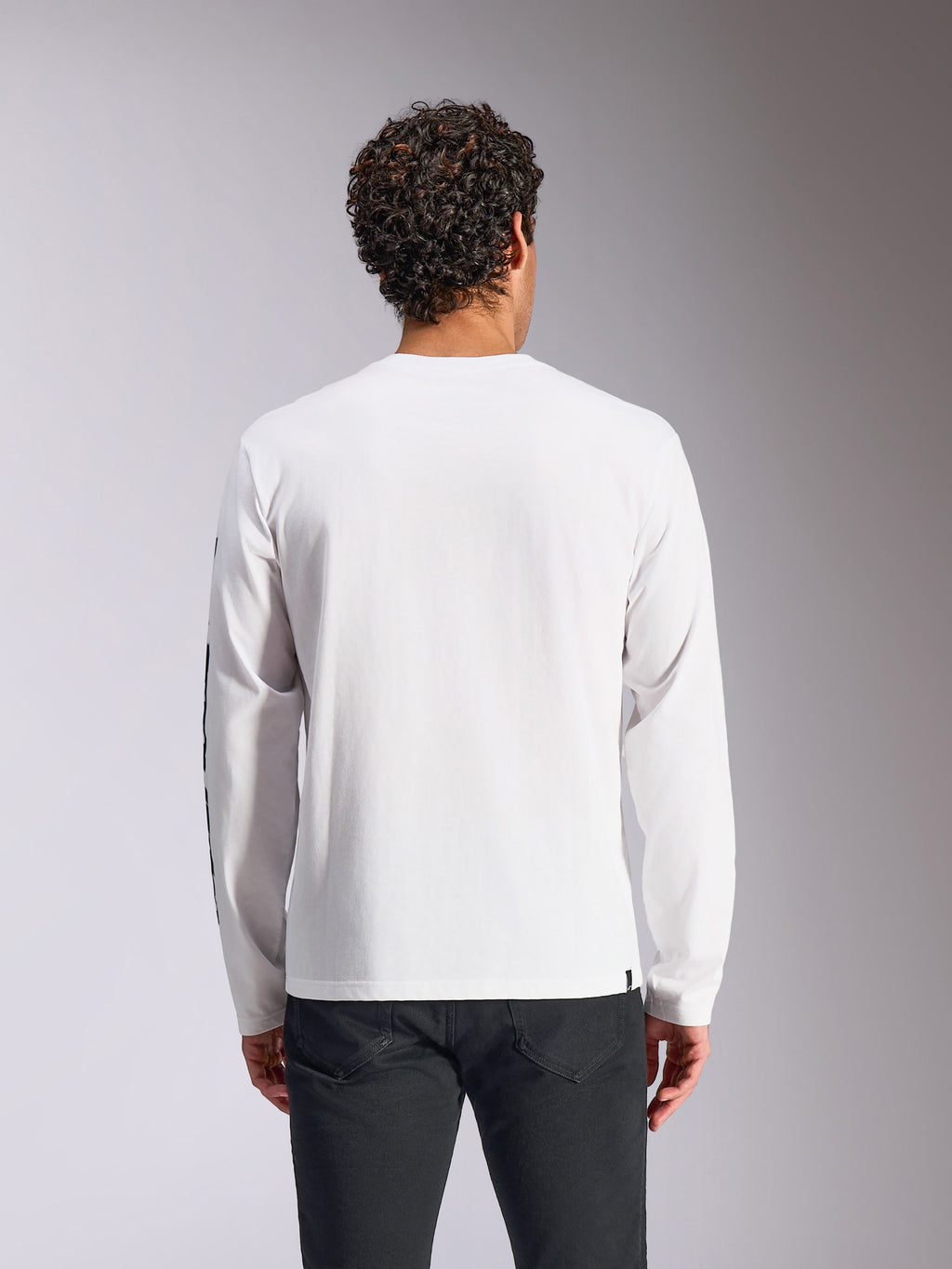 Alpinestars Trackside CSF Tee - Maniche Lunghe, bianco, vista posteriore su modello, abbinata a pantaloni neri, tessuto bianco pulito con maniche lunghe, streetwear casual ispirato al motorsport