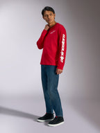 Alpinestars Trackside CSF Long Sleeve Tee, rossa con logo Alpinestars bianco su petto e manica, indossata da un modello con jeans blu e sneakers nere, streetwear casual ispirato al motorsport