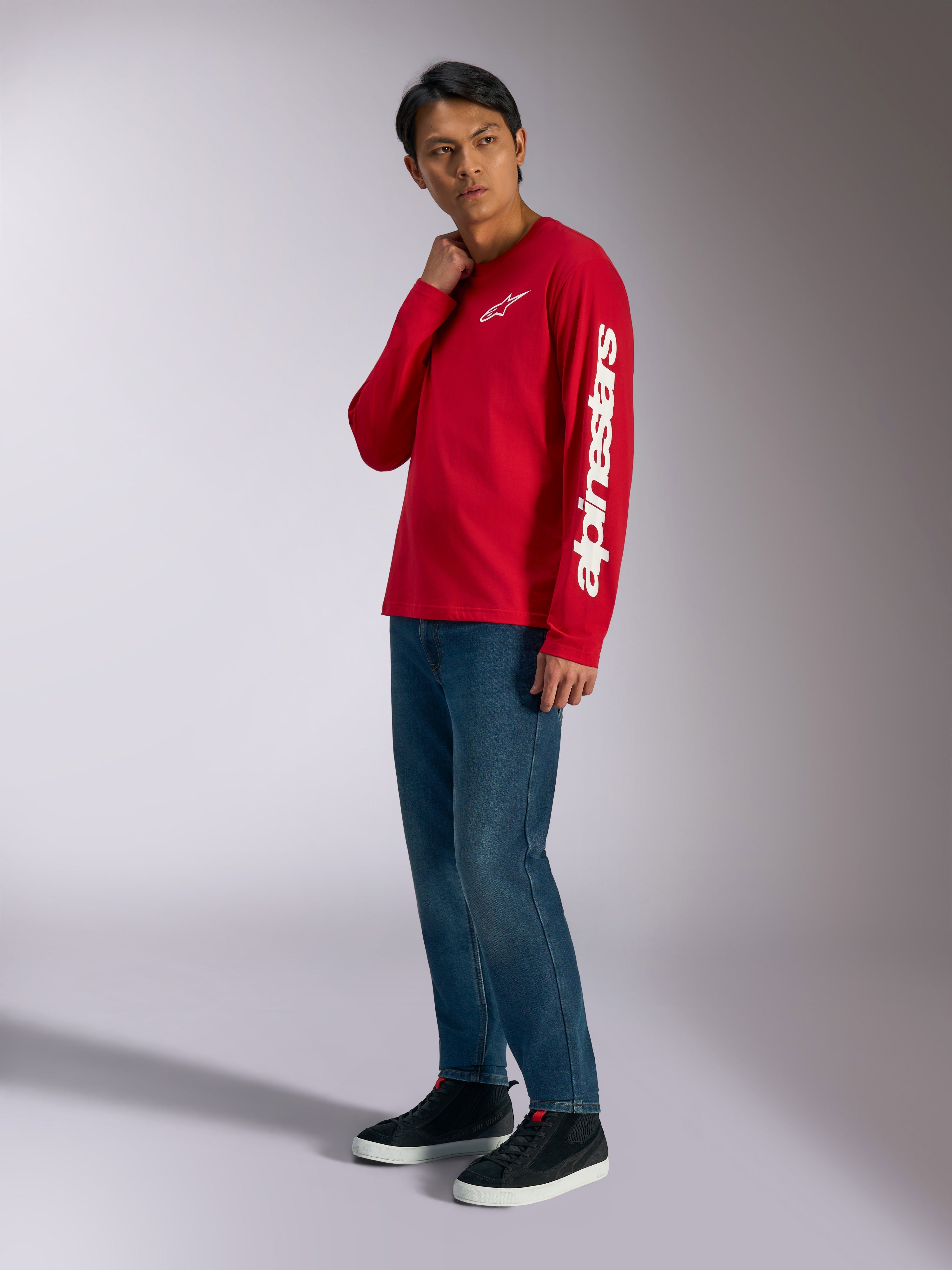 Alpinestars Trackside CSF Long Sleeve Tee, rossa con logo Alpinestars bianco su petto e manica, indossata da un modello con jeans blu e sneakers nere, streetwear casual ispirato al motorsport