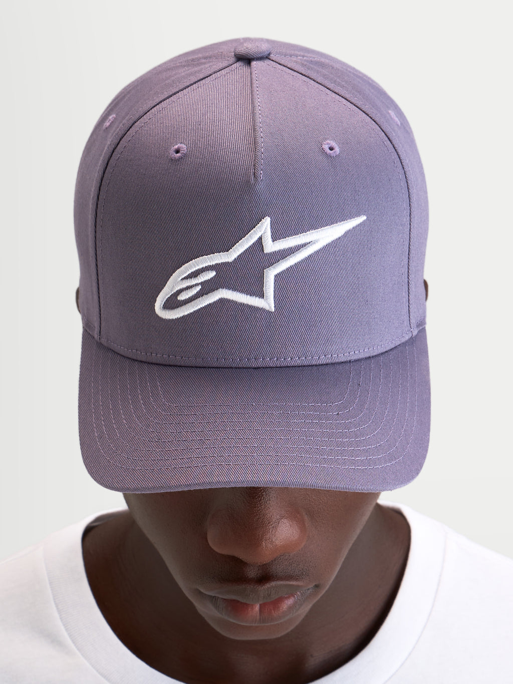 Alpinestars Cappello Ageless Snapback, cappello sportswear casual in viola e bianco, con visiera curva, corona strutturata e logo Astars ricamato in 3D sul davanti, indossato da un modello