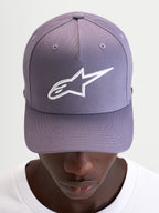 Alpinestars Cappello Ageless Snapback, cappello sportswear casual in viola e bianco, con visiera curva, corona strutturata e logo Astars ricamato in 3D sul davanti, indossato da un modello