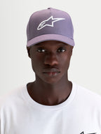 Alpinestars Cappello Ageless Snapback, cappello sportswear con visiera curva, viola e bianco, indossato da un modello che mostra il logo Astars ricamato in 3D sul davanti e il profilo in twill strutturato