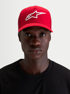 Alpinestars Cappello Ageless Snapback, cappello sportswear rosso indossato da un modello, con logo Astars ricamato in 3D bianco, visiera curva e corona strutturata in twill di cotone
