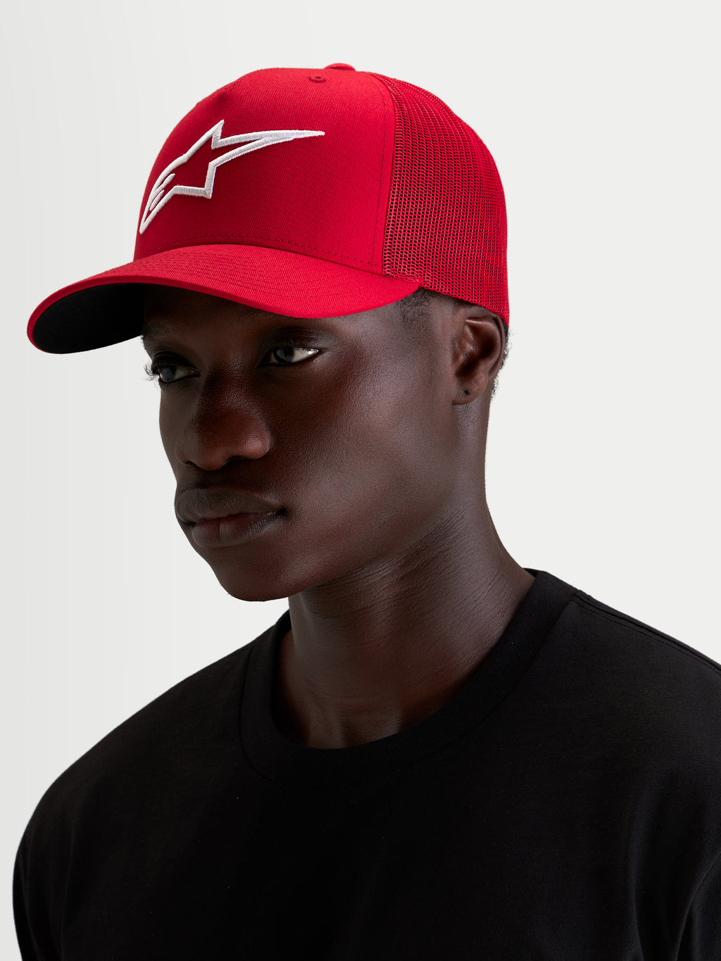 Alpinestars Cappello Ageless Snapback, cappello sportswear rosso e bianco indossato da un modello, con visiera curva e logo 3D ricamato in evidenza