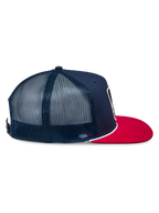 Cappello Alpinestars Control Trucker, blu navy e rosso, vista laterale di profilo che mostra la parte anteriore in twill navy e i pannelli posteriori in rete, visiera piatta rossa con dettaglio in corda intrecciata bianca, copricapo casual ispirato al motorsport
