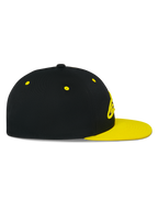 Cappello Snapback Alpinestars Thickness, vista laterale, corona nera con visiera piatta e occhielli giallo fluo, logo ricamato in 3D sul davanti, copricapo casual ispirato al motorsport