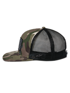 Cappello Alpinestars Flag Flat Trucker, mimetico verde e nero, visiera piatta e corona strutturata, parte anteriore in twill mimetico e retro in rete nera, vista laterale con patch a bandiera e logo ricamato, streetwear casual ispirato al motorsport