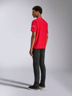 Alpinestars Frontal CSF Tee, maglietta a maniche corte, rosso, vista posteriore su modello, con logo bianco sulla manica, abbinata a pantaloni neri, streetwear casual ad alte prestazioni