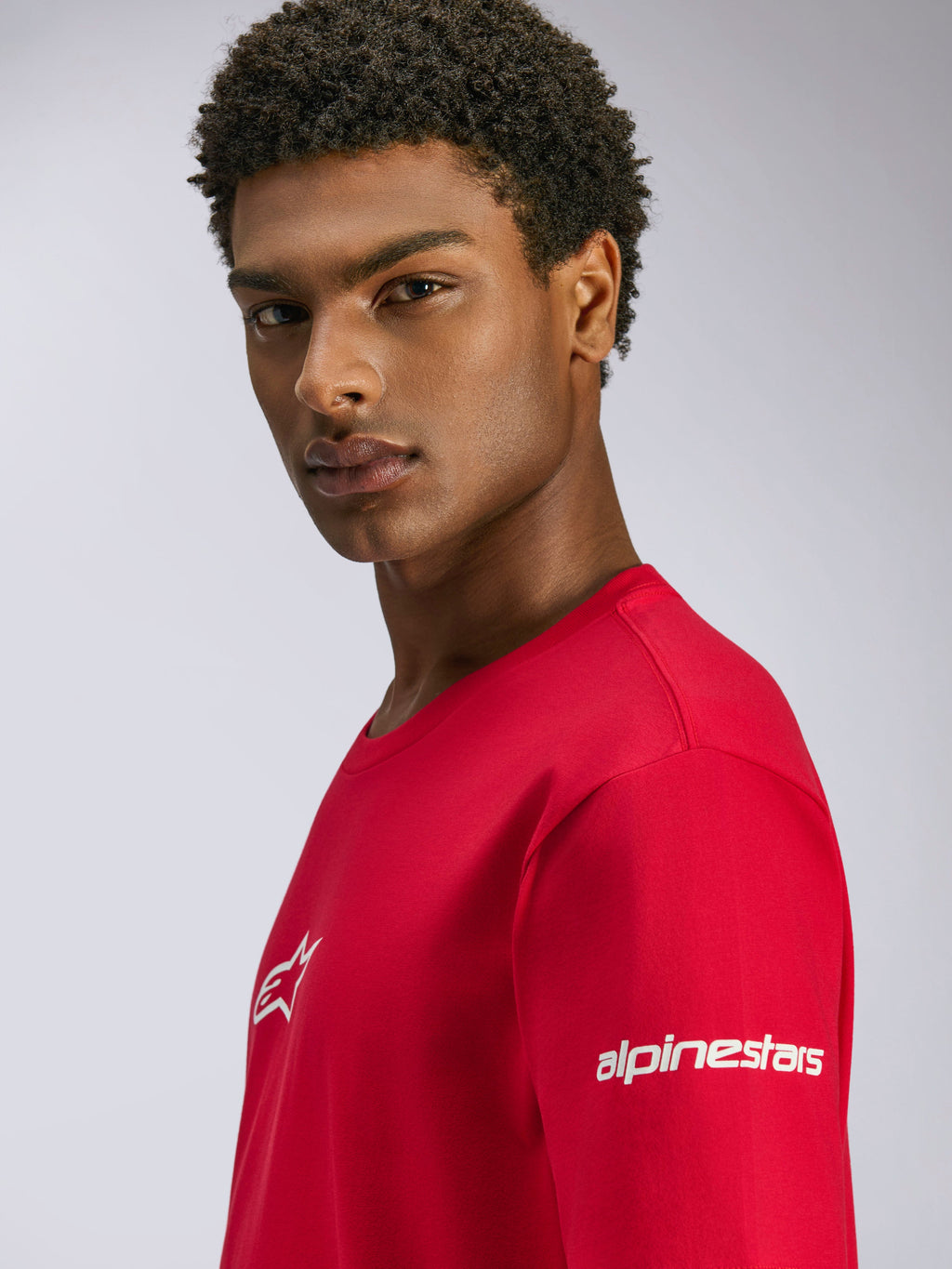 Alpinestars Frontal CSF Tee, t-shirt a maniche corte rossa, con loghi bianchi sul petto e sulla manica, indossata da un modello, streetwear casual performance motorsport