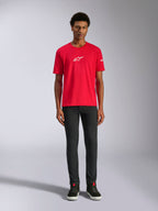 Alpinestars Frontal CSF Tee, maglia a maniche corte, rossa, piccolo logo Astars bianco sul petto, indossata da un modello con pantaloni e scarpe neri, abbigliamento sportivo casual ad alte prestazioni
