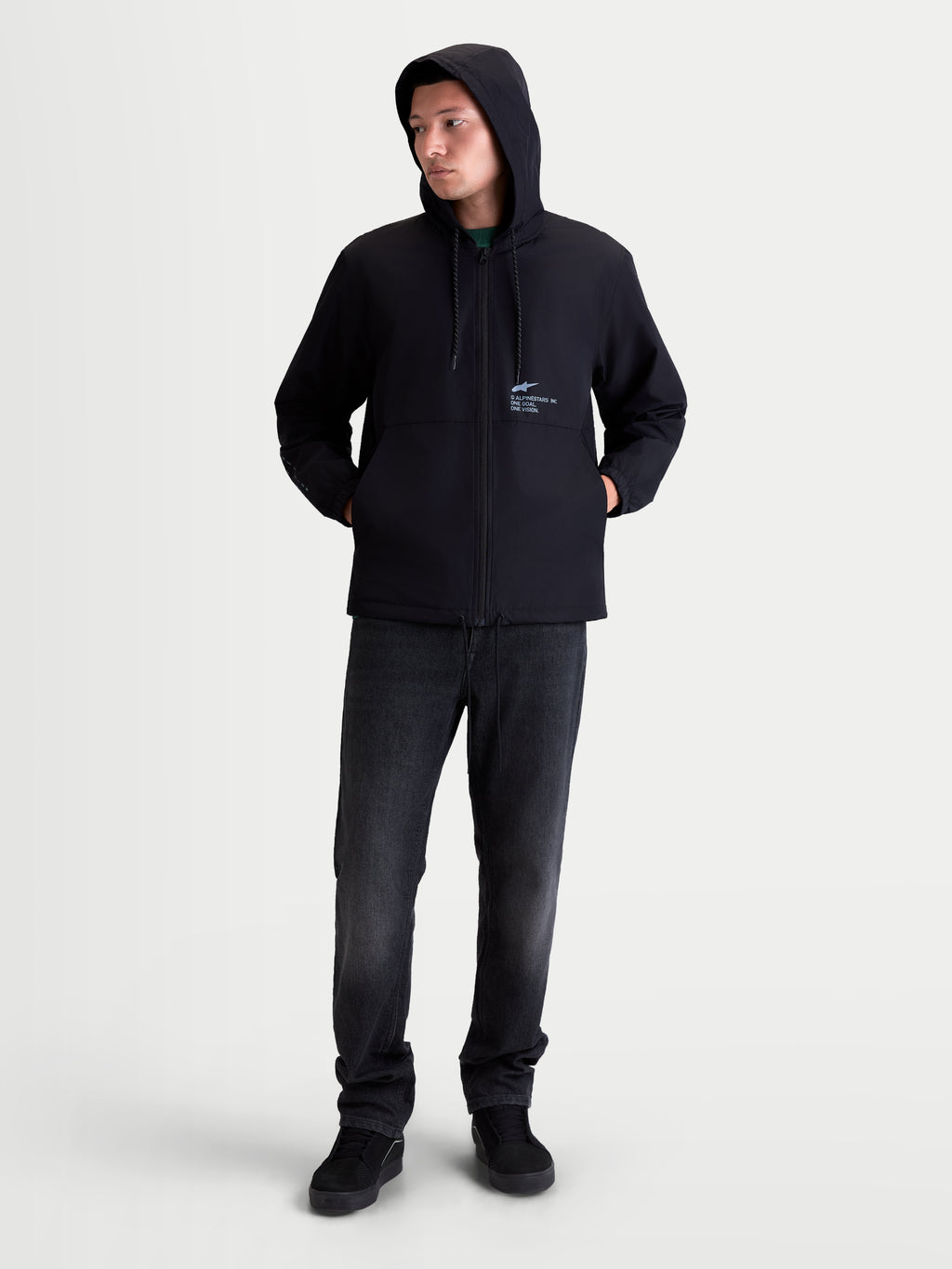 Alpinestars Giacca Frangivento Speeder Resolve, giacca sportswear leggera da uomo, nera, in poliestere con cappuccio regolabile e fodera interna in rete. Vista intera su modello per un look urban e casual quotidiano con branding Alpinestars sul petto.