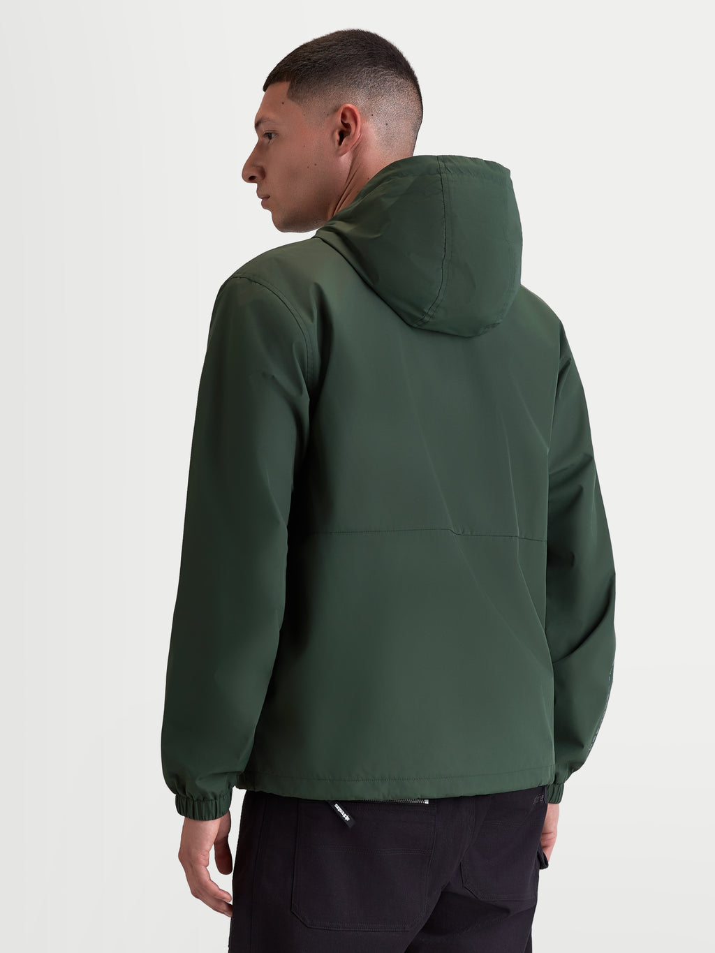 Alpinestars Giacca frangivento Speeder Resolve, giacca sportswear leggera con cappuccio per uso urbano, verde, in poliestere antivento con fodera in rete, vista posteriore su modello che mostra il design pulito della schiena e i polsini elastici.