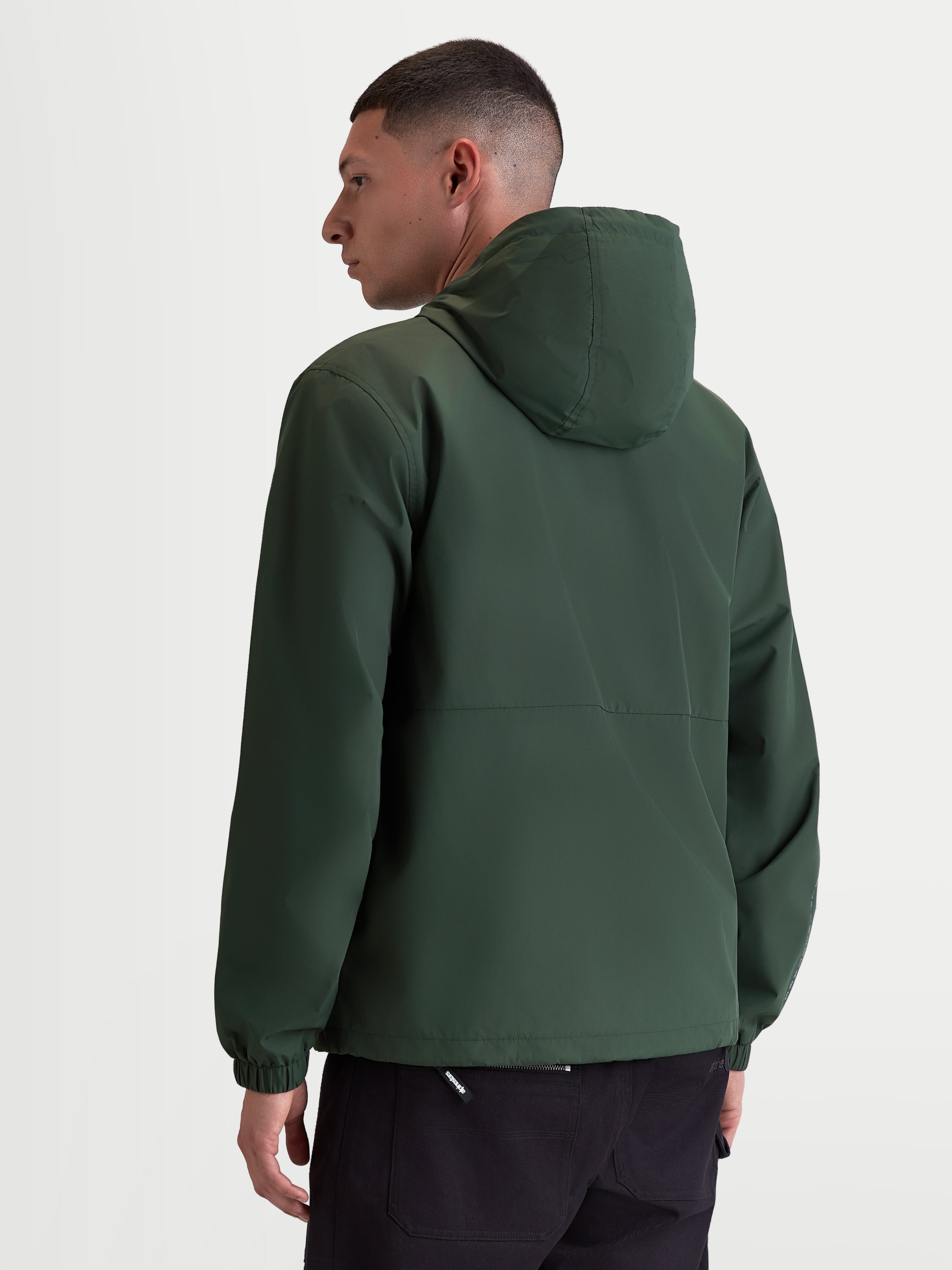 Alpinestars Giacca frangivento Speeder Resolve, giacca sportswear leggera con cappuccio per uso urbano, verde, in poliestere antivento con fodera in rete, vista posteriore su modello che mostra il design pulito della schiena e i polsini elastici.