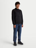 Alpinestars Felpa Apera Half-Zip, pullover sportswear unisex con chiusura mezza zip e tasca a marsupio, nero, in pile tri-blend, indossata da un modello con jeans blu, stile casual ispirato al motorsport