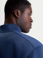 Alpinestars Felpa Apera Half-Zip, felpa sportswear blu, vista posteriore ravvicinata su modello con stampa logo HD tonale sulla spalla, tessuto in pile tri-blend premium, stile casual motorsport