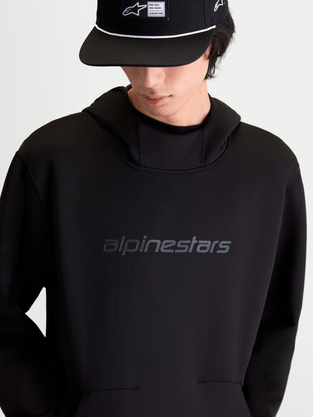 Alpinestars Felpa con cappuccio Datrix, felpa sportswear pullover nera in pile tri-blend double-face, con logo Alpinestars HD tono su tono sul petto, cappuccio foderato in rete e tasca con dettaglio a freccia, vista frontale su modello.