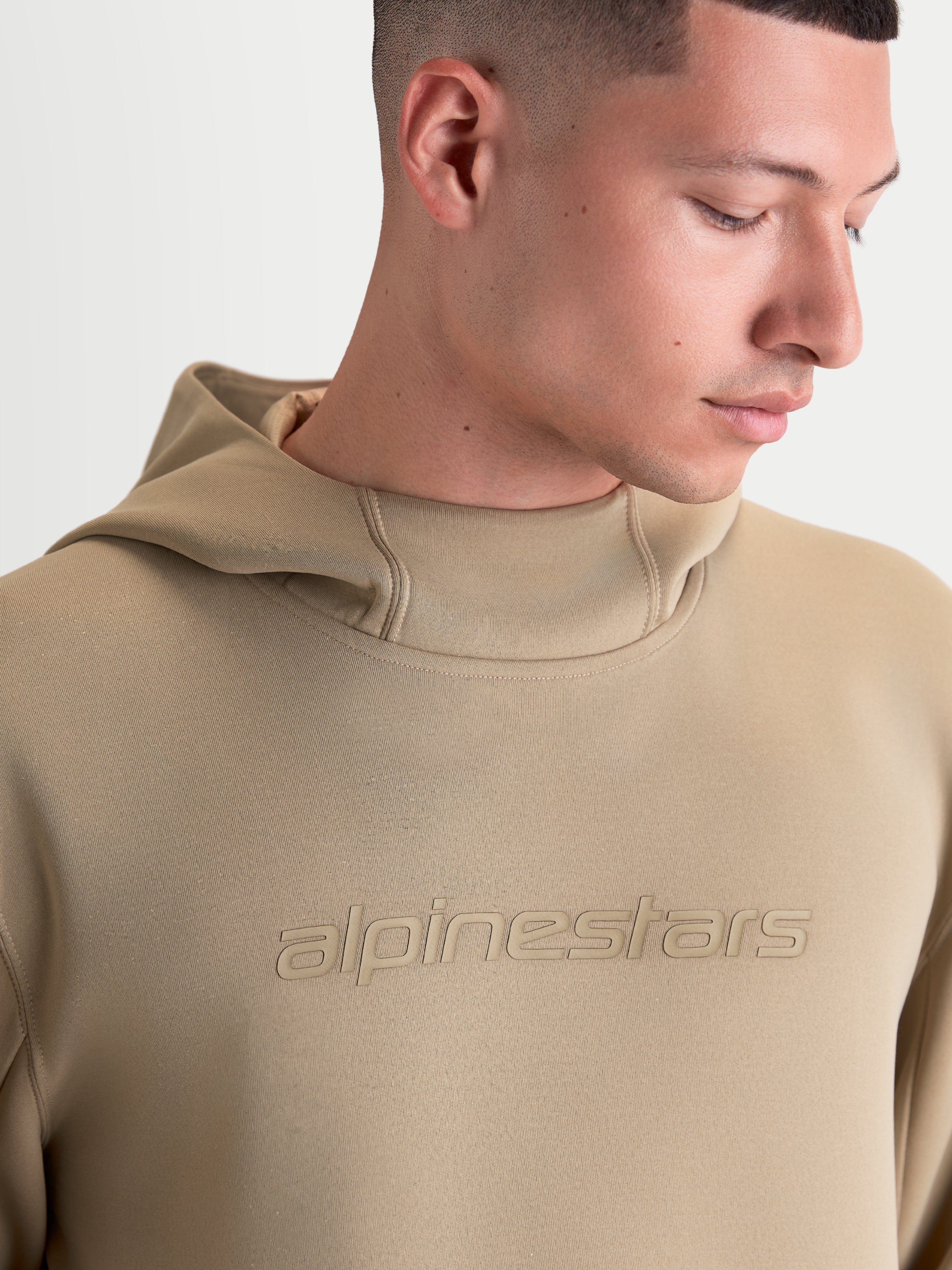 Alpinestars Felpa con cappuccio Datrix, felpa sportswear per uomo e donna, marrone, con logo Alpinestars tono su tono e cappuccio foderato in rete, primo piano su modello che mostra la costruzione in pile premium.