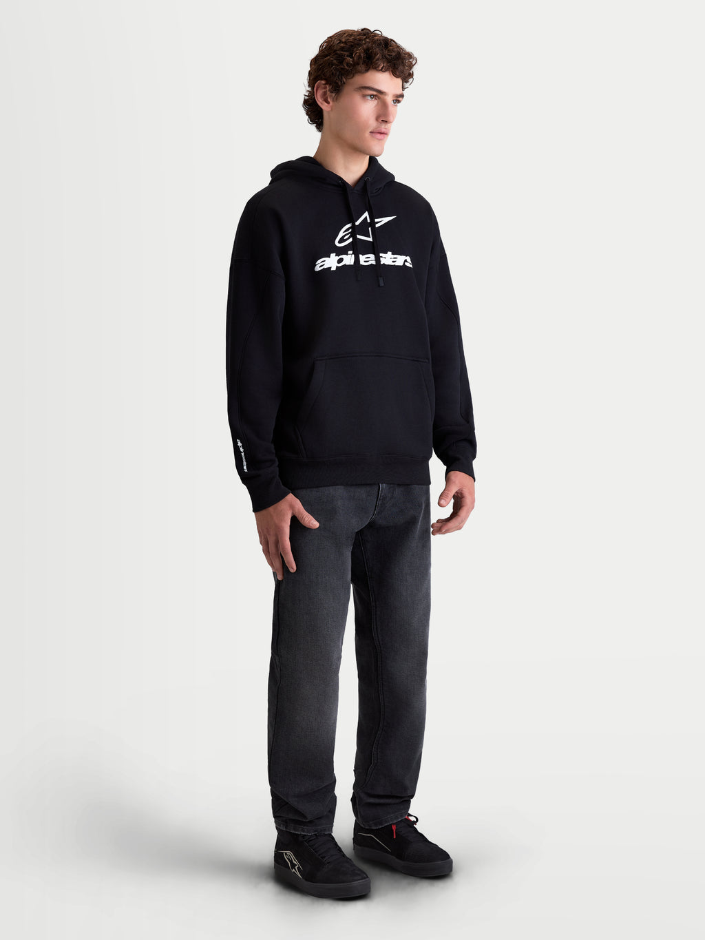 Alpinestars Felpa con cappuccio Prelude Oversized, felpa sportswear da uomo in pile, nera con logo bianco a rilievo sul petto, vestibilità oversize e tasca a marsupio, indossata da un modello