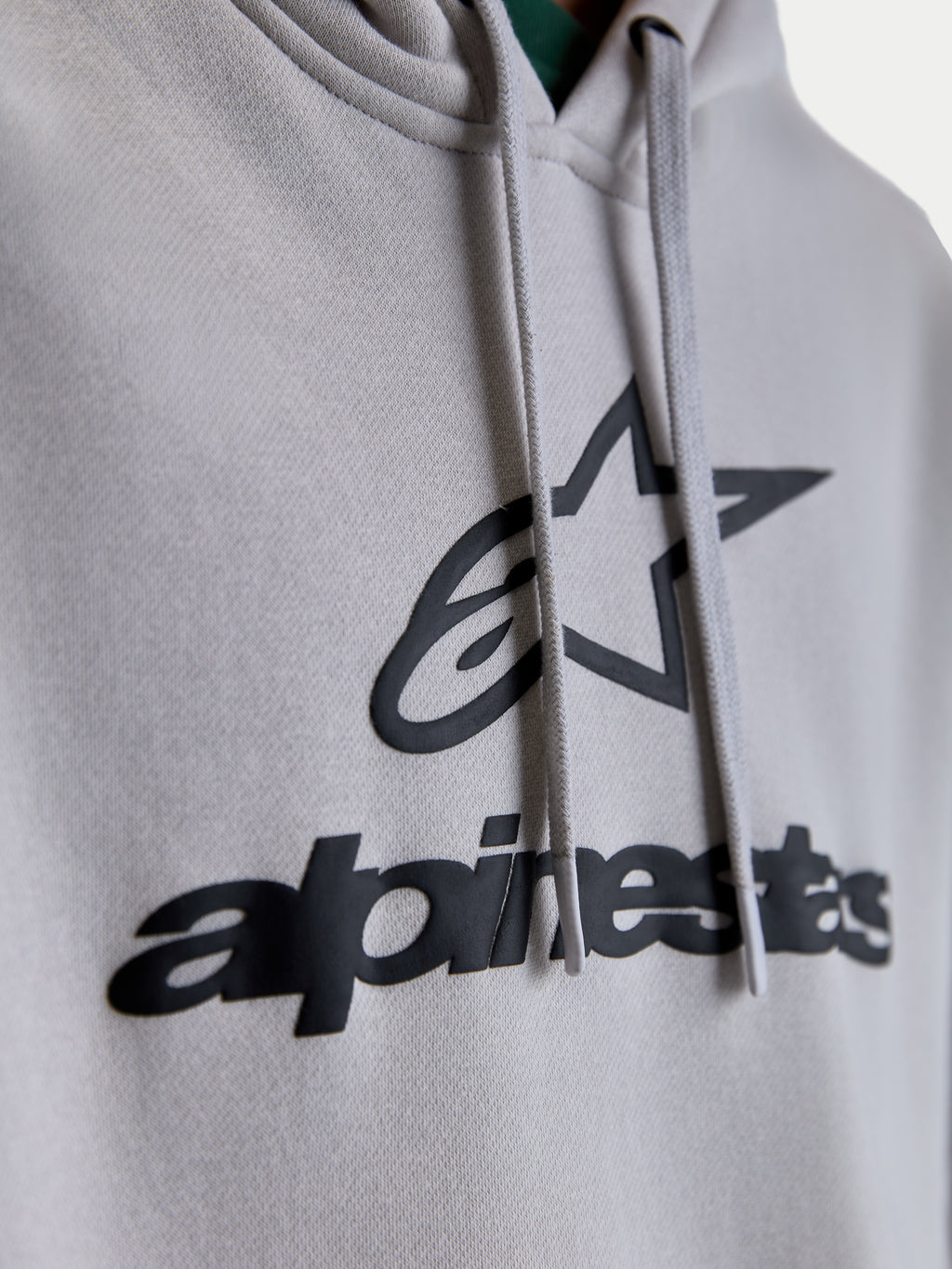 Alpinestars Felpa con cappuccio Prelude Oversized, dettaglio del logo con stampa a rilievo e grafica a stella neri su pile grigio cemento, cordini piatti, sportswear premium unisex