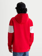 Alpinestars Felpa con cappuccio Cubic, felpa sportswear in pile, rossa e bianca, vista posteriore su modello con cappellino nero, maniche con design a blocchi di colore, cappuccio foderato e polsini a coste, stile motorsport casual.
