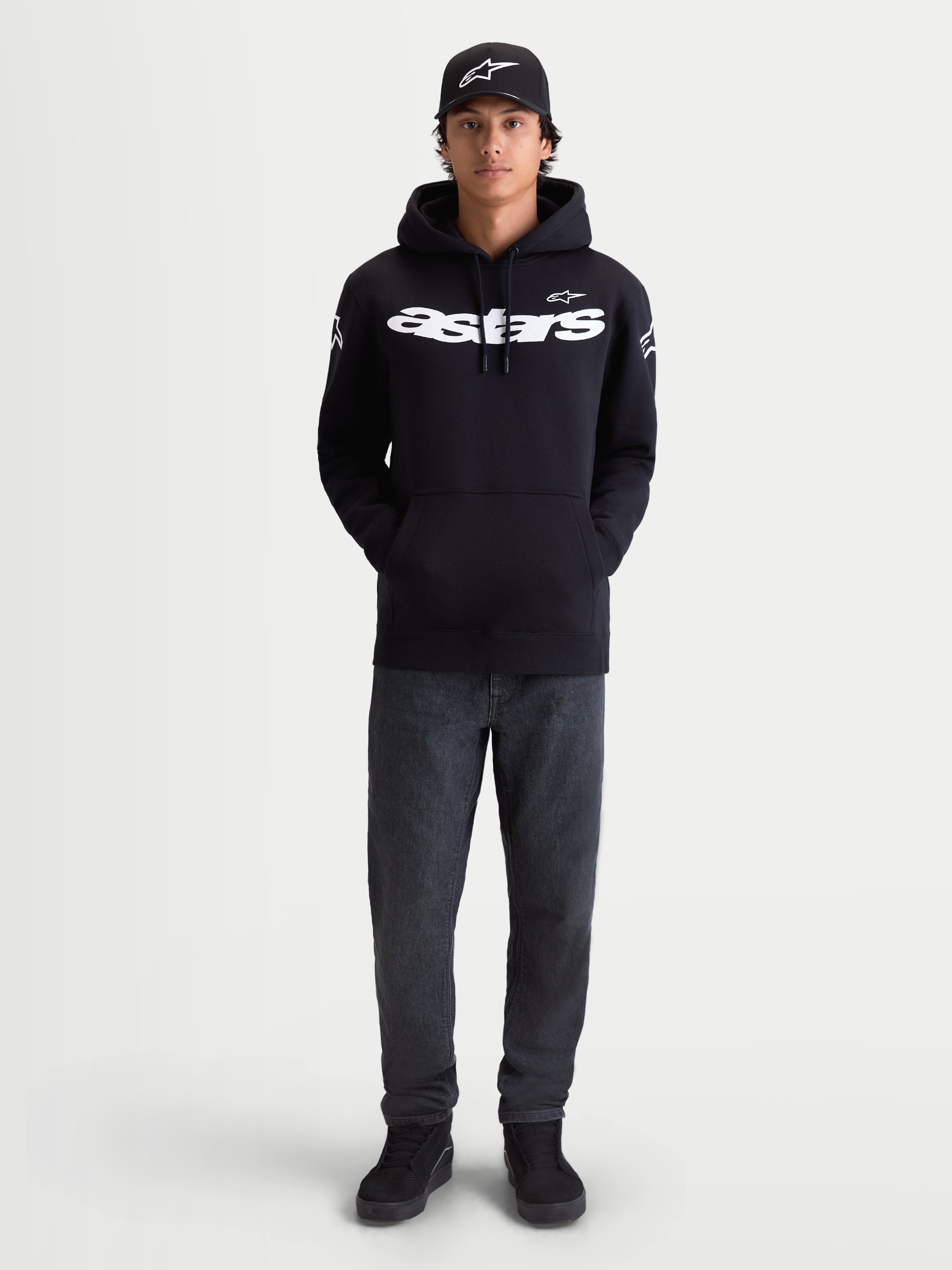 Alpinestars felpa con cappuccio Velocifier, sportswear casual da uomo per uso off-bike, nera e bianca, in misto cotone premium. Caratterizzata dalla scritta Astars curva sul petto e loghi sulle spalle, mostrata su un modello con cappellino coordinato.