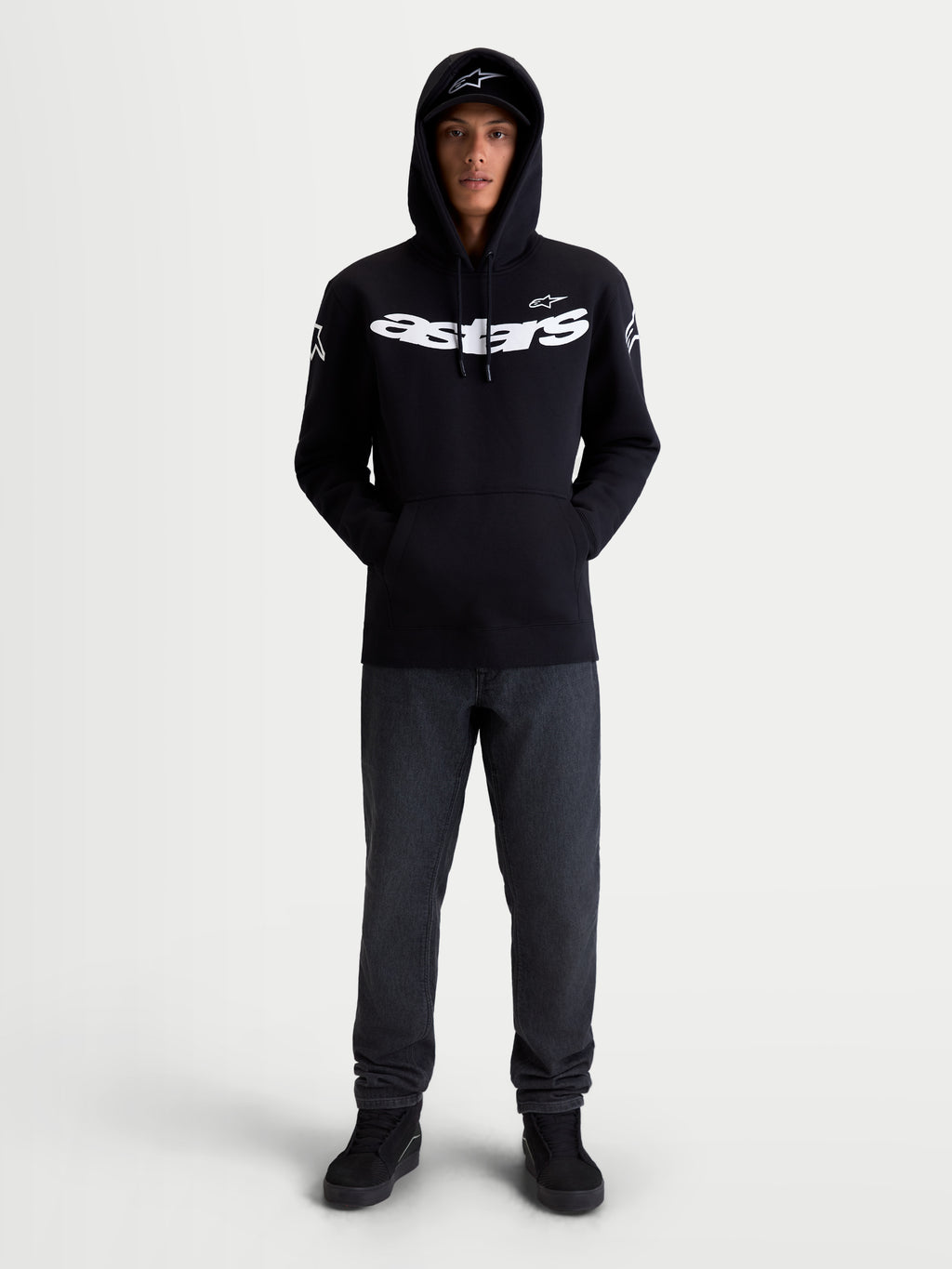Alpinestars Felpa con cappuccio Velocifier, pullover in pile da sportswear da moto unisex, nera e bianca, in misto cotone e poliestere riciclato, con grande scritta Astars sul petto e loghi sulle spalle, vista frontale su modello per abbigliamento casual off-bike.
