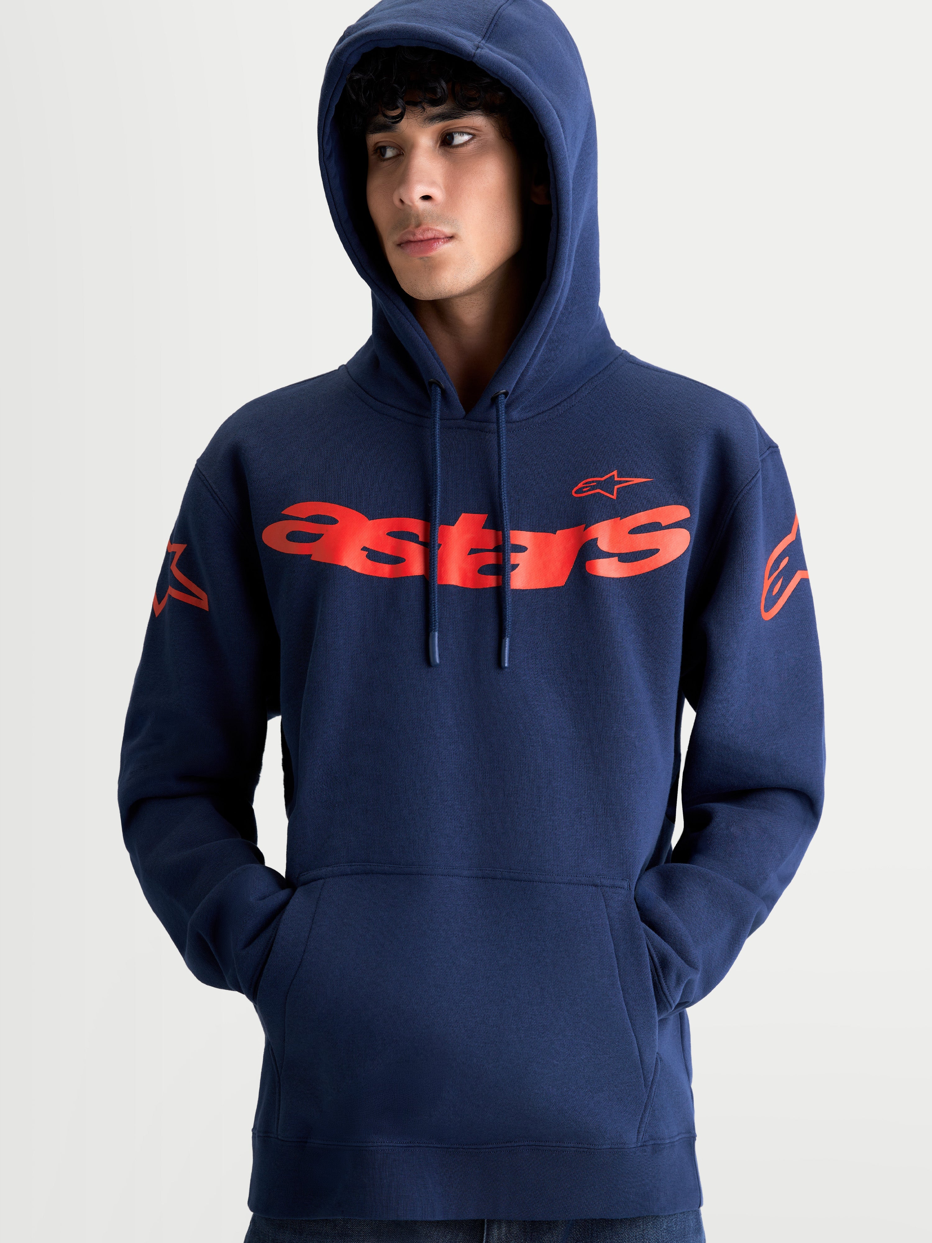 Alpinestars Felpa con cappuccio Velocifier, felpa sportswear unisex, blu navy e rosso, con scritta Astars curva sul petto e loghi sulle spalle, cappuccio con cordini, stile casual motorsport, indossata da un modello.