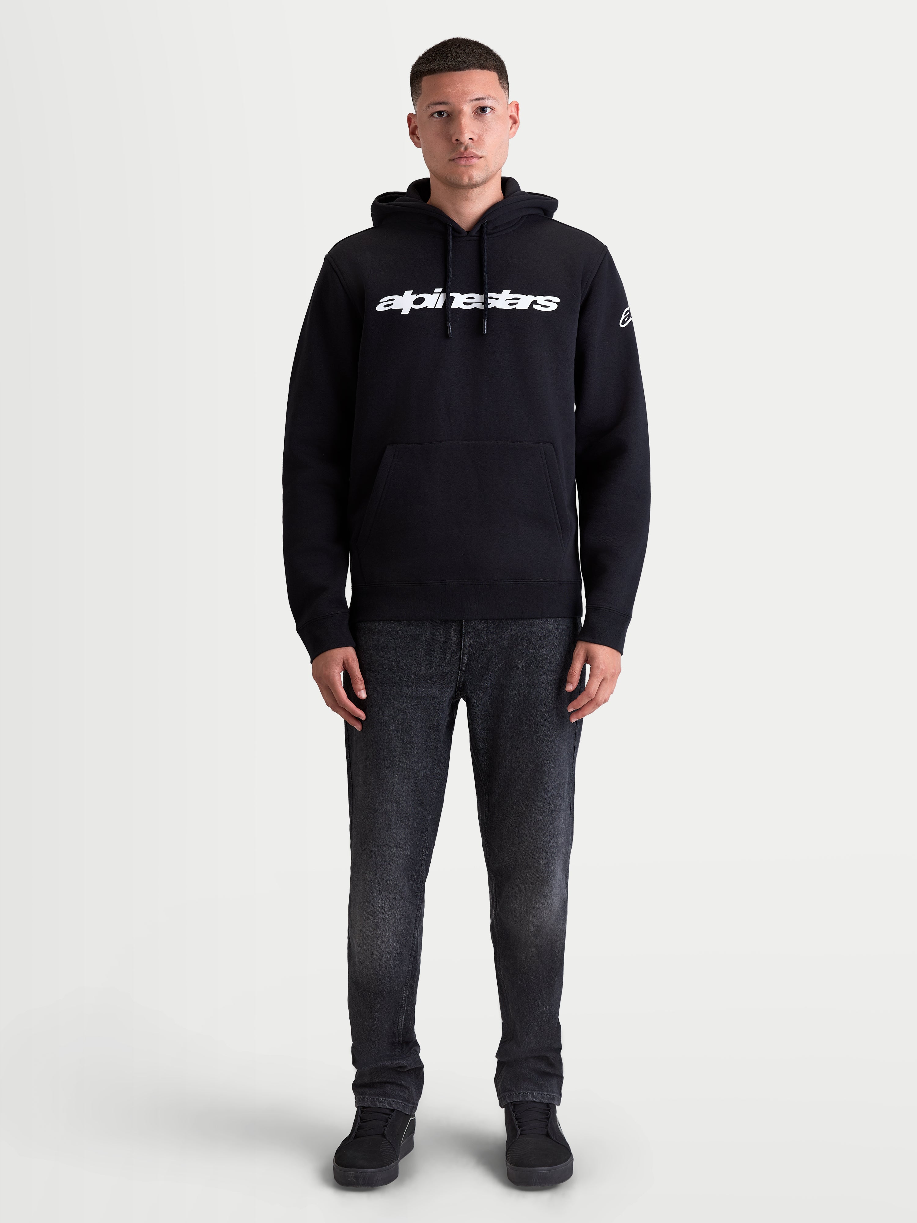 Alpinestars felpa con cappuccio Race Wordmark, felpa sportswear casual da uomo, nera e bianca, con logo frontale Race Linear Word e grafica Ageless sulla manica, in pile di misto cotone e poliestere riciclato, indossata da un modello.
