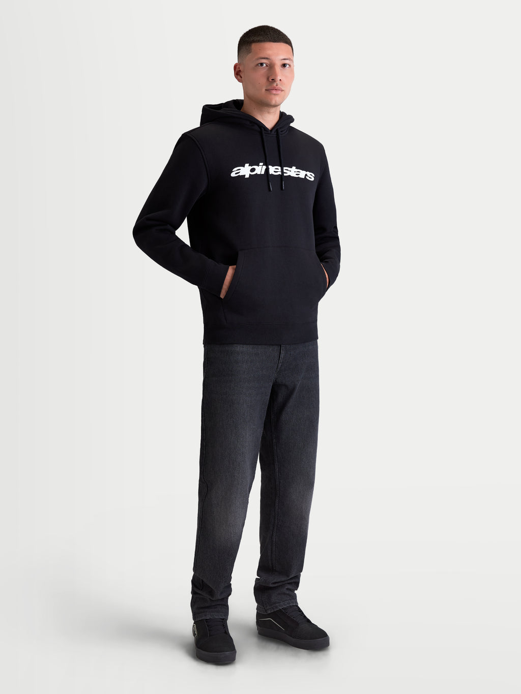 Alpinestars felpa con cappuccio Race Wordmark, felpa in pile sportswear da uomo, nera con logo lineare bianco sul petto, cappuccio con cordini e tasca a marsupio, modello che indossa il prodotto.