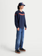 Alpinestars Maglietta Velocifier CSF, maglietta a maniche lunghe da uomo, blu navy e arancione, in misto cotone e poliestere riciclato, con grafica Astars curva sul petto e loghi sulle spalle, stile sportswear casual ispirato al motorsport.