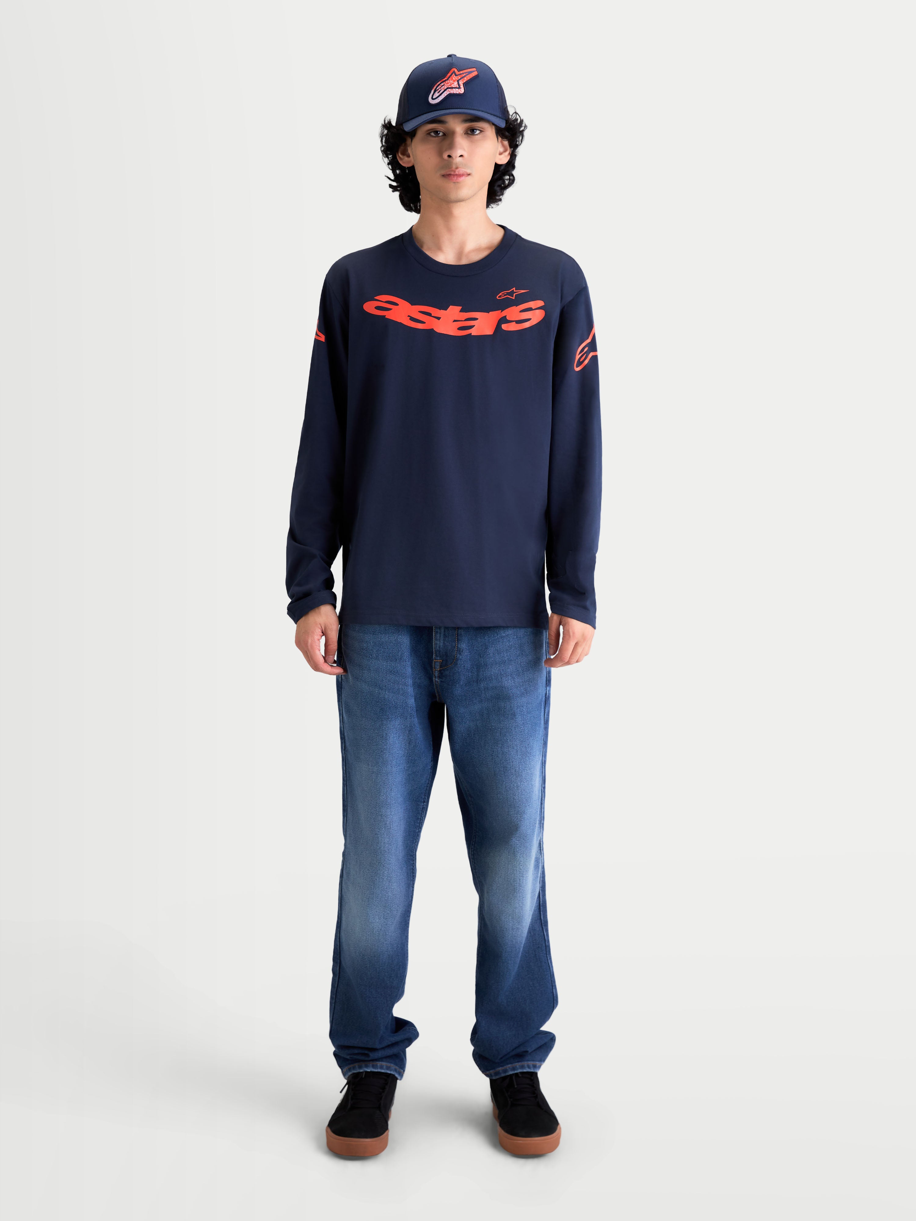 Alpinestars Maglietta Velocifier CSF, maglietta a maniche lunghe da uomo indossata da un modello, blu navy e rosso, con grafica Astars curva sul davanti e loghi sulle spalle, stile casual ispirato al motorsport