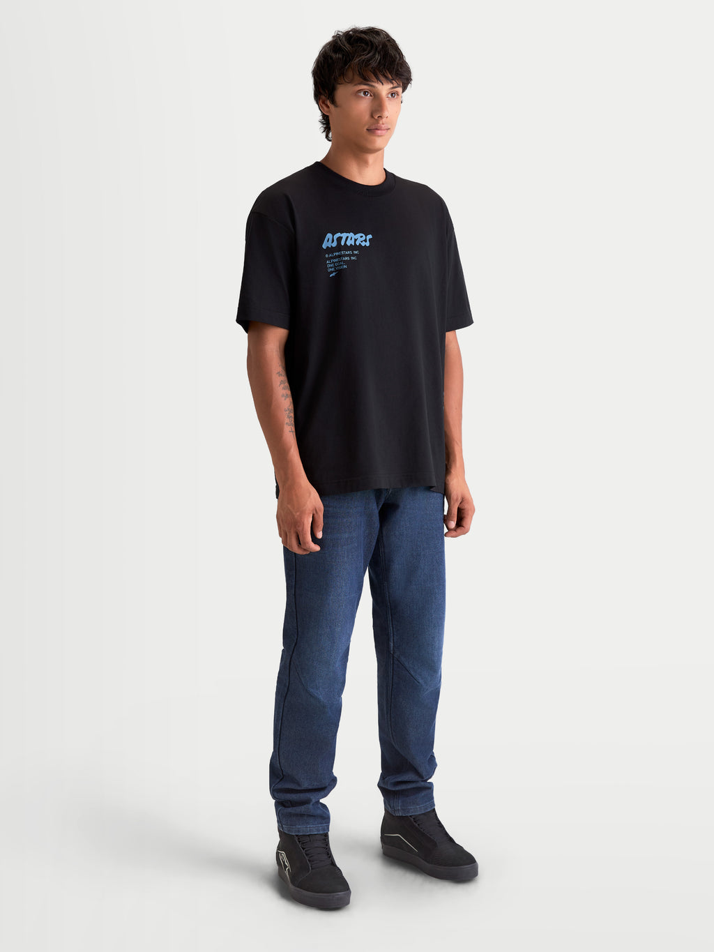 Alpinestars Maglietta Chalk Oversized CSF, maglietta a maniche corte sportswear da uomo, nera con grafica Astars blu, vestibilità oversize, 60% cotone e 40% poliestere, indossata da un modello per un look casual motorsport.