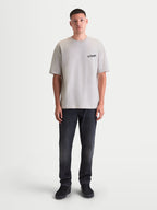 Alpinestars Maglietta Latitude Oversized CSF, maglietta da uomo a maniche corte grigio cemento, vestibilità oversize rilassata con grafica wordmark ASTARS sul petto, misto cotone e poliestere, vista frontale a figura intera su modello.