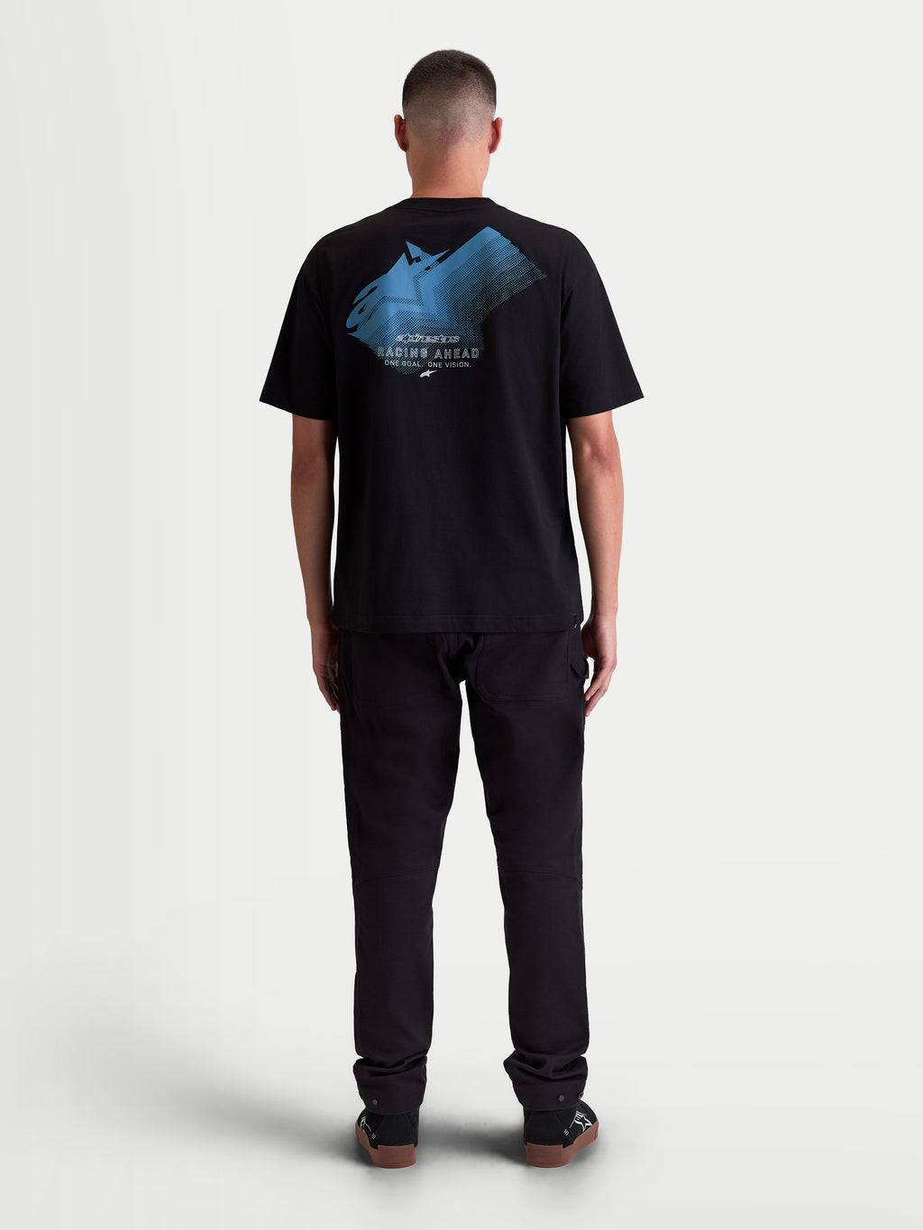 Alpinestars Maglietta Ghost Oversized CSF, maglietta a maniche corte da uomo, nera, vestibilità oversize rilassata, grafica con logo sfumato blu sul retro e scritte Racing Ahead e One Goal. One Vision., abbigliamento lifestyle motorsport, vista posteriore su modello.