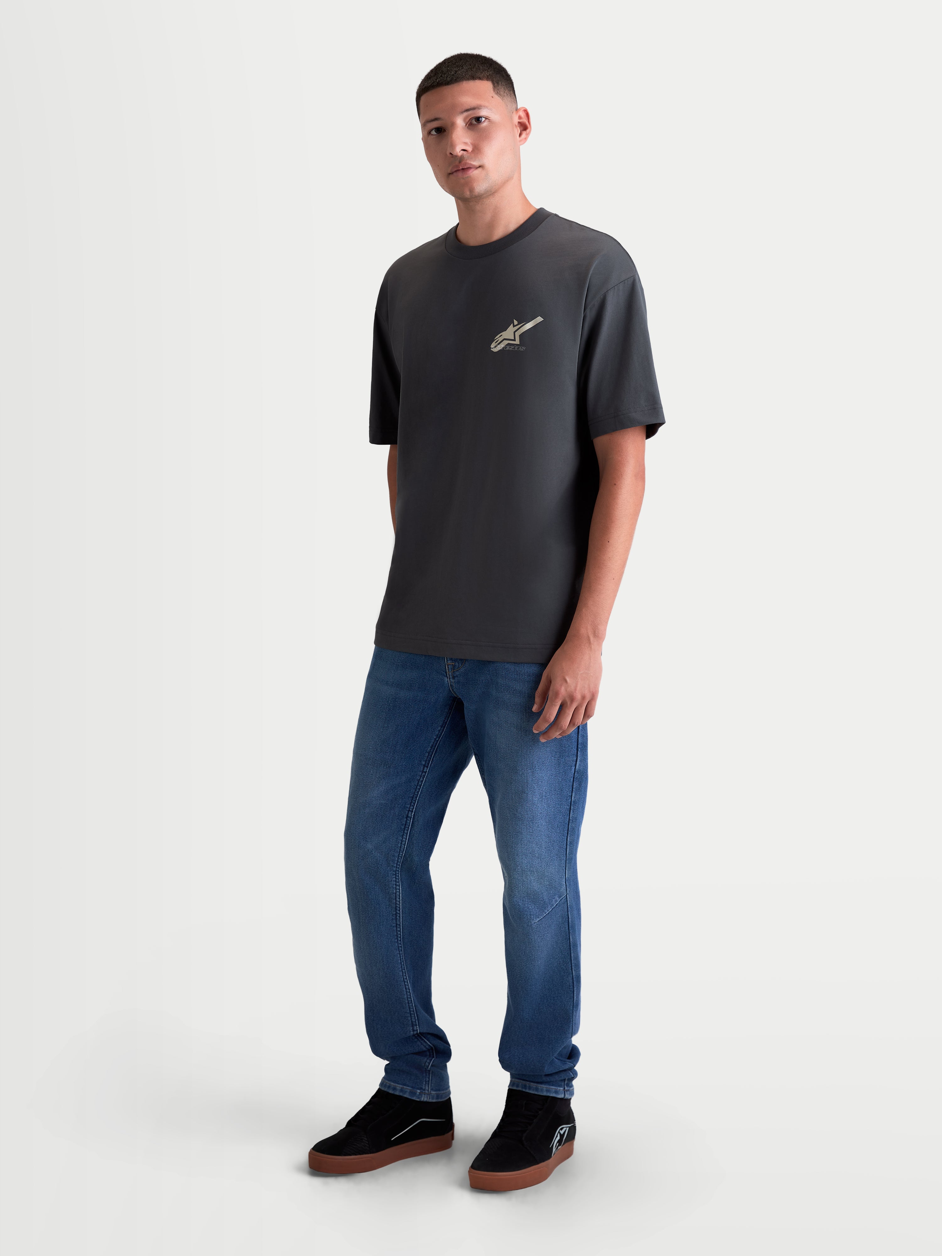 Alpinestars Maglietta Ghost Oversized CSF, maglietta a maniche corte da uomo, grigio antracite, vestibilit  oversize rilassata, logo Astars stampato sul petto, indossata da un modello con jeans blu, stile sportswear
