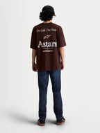 Alpinestars Maglietta Post Oversized CSF, maglietta a maniche corte marrone, vestibilità oversized, grafiche bianche sul retro con logo Astars World Wide e scritta One Goal. One Vision., stile sportswear casual unisex