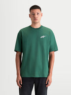 Alpinestars Maglietta Checkback Oversized CSF, maglietta sportswear da uomo a maniche corte, verde e bianca, vista frontale su modello, con vestibilità oversized rilassata e iconico logo Astars sul petto, top casual in misto cotone e poliestere ispirato al motorsport.