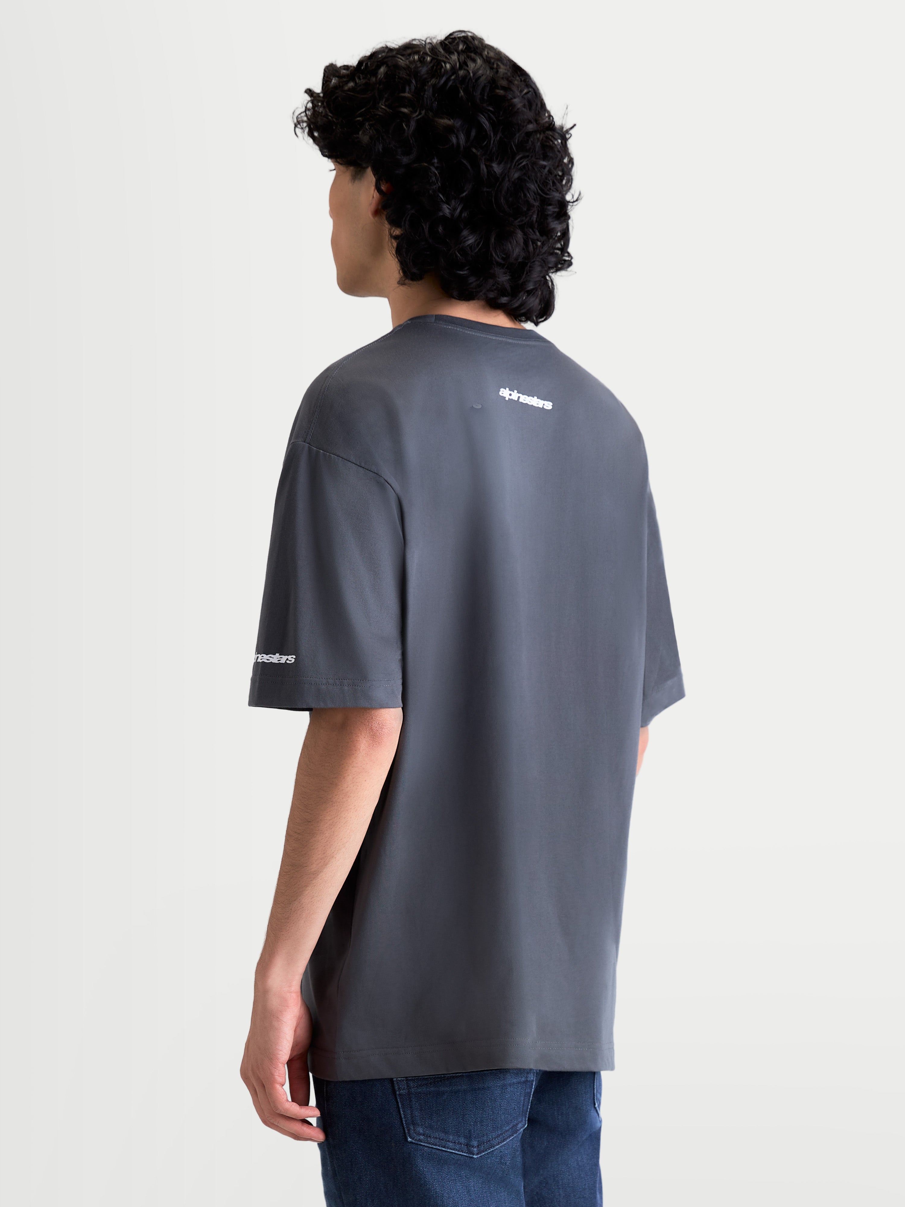 Alpinestars maglietta Mandate Oversized CSF, maglietta a maniche corte sportswear, grigia, logo bianco in puff print sulla schiena e sulla manica, vestibilità oversized rilassata, tessuto misto cotone e poliestere, vista posteriore su modello