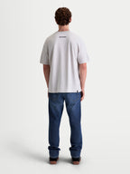 Alpinestars Maglietta Prelude Oversized CSF, maglietta a maniche corte da uomo, grigio cemento, vista posteriore su modello con piccolo logo Alpinestars nero sulla schiena, vestibilità rilassata e stile sportswear casual.