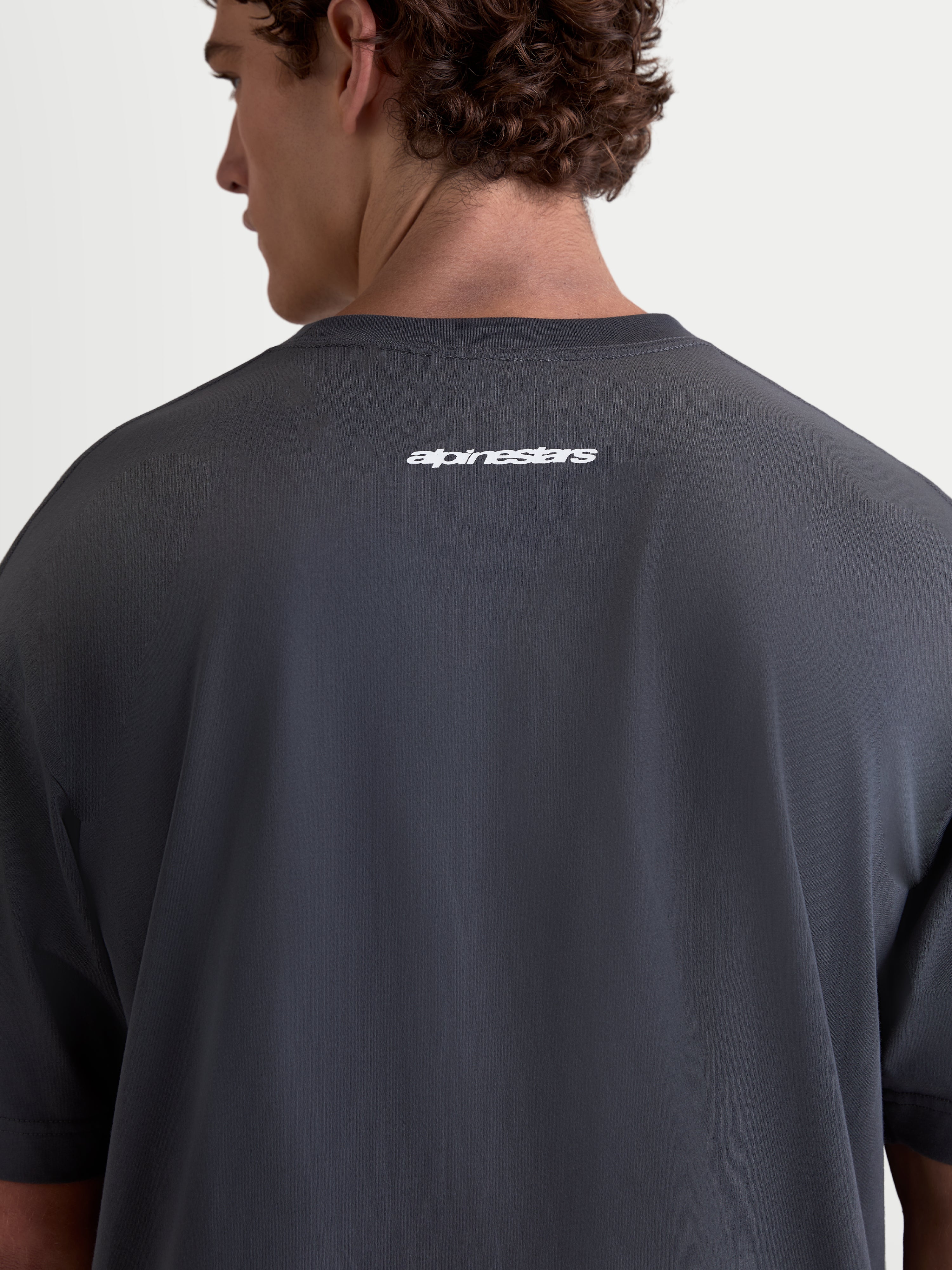 Alpinestars Maglietta Prelude Oversized CSF, maglietta sportswear a maniche corte grigio scuro, vista posteriore su modello con logo Alpinestars bianco sulla schiena, vestibilità oversized casual
