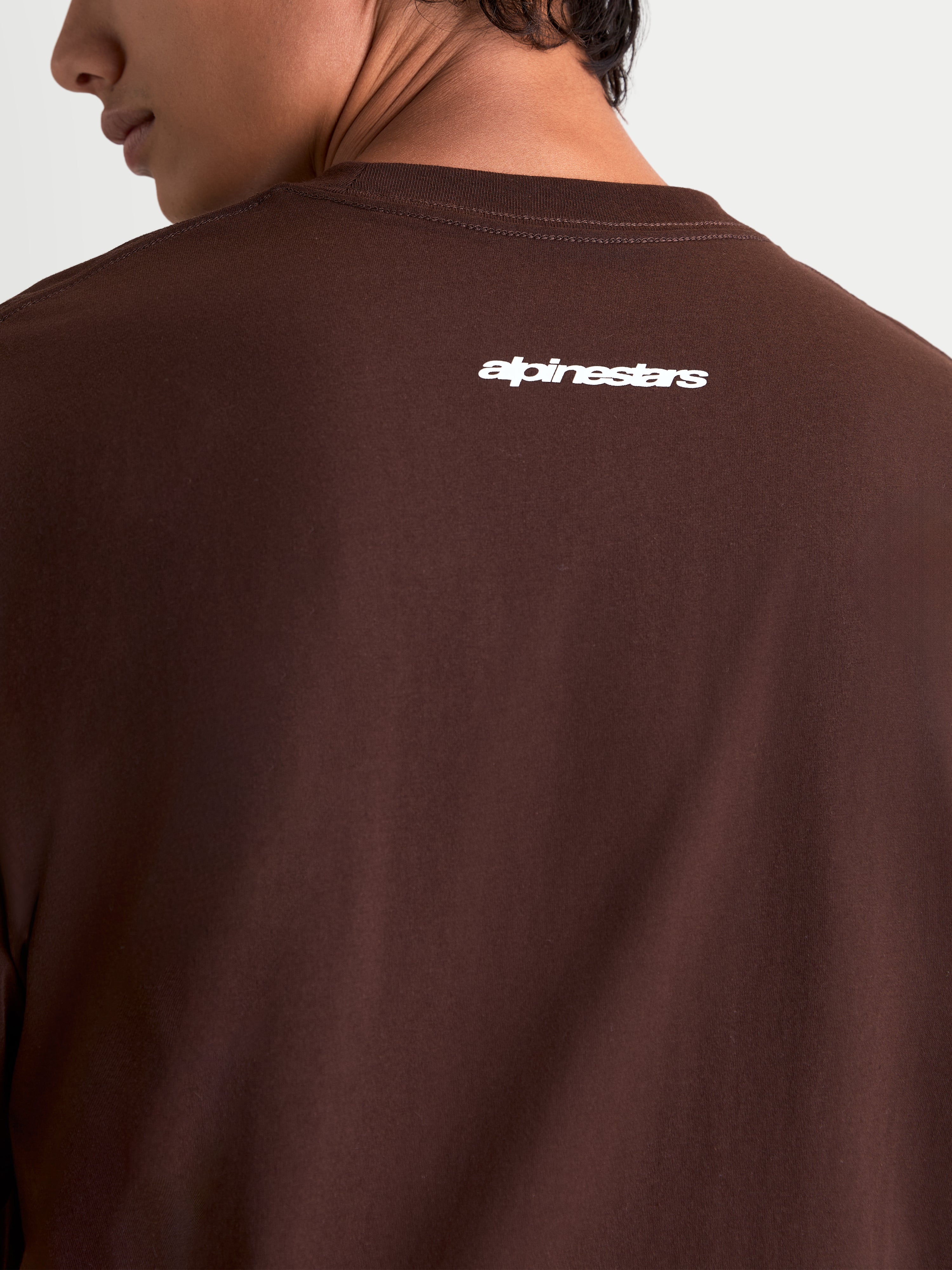 Alpinestars Maglietta Prelude Oversized CSF, maglietta a maniche corte marrone con logo Alpinestars bianco stampato sulla schiena, vestibilità oversized rilassata, stile sportswear casual ispirato al motorsport.