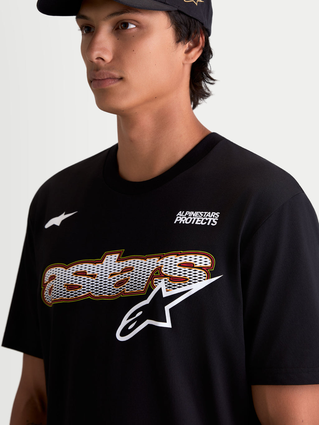 Alpinestars Maglietta Cypress CSF, maglietta da uomo a maniche corte, nera, primo piano indossata con grafica frontale con riempimento mesh, logo Alpinestars Protects e logo Astars bianco, tessuto premium in misto cotone