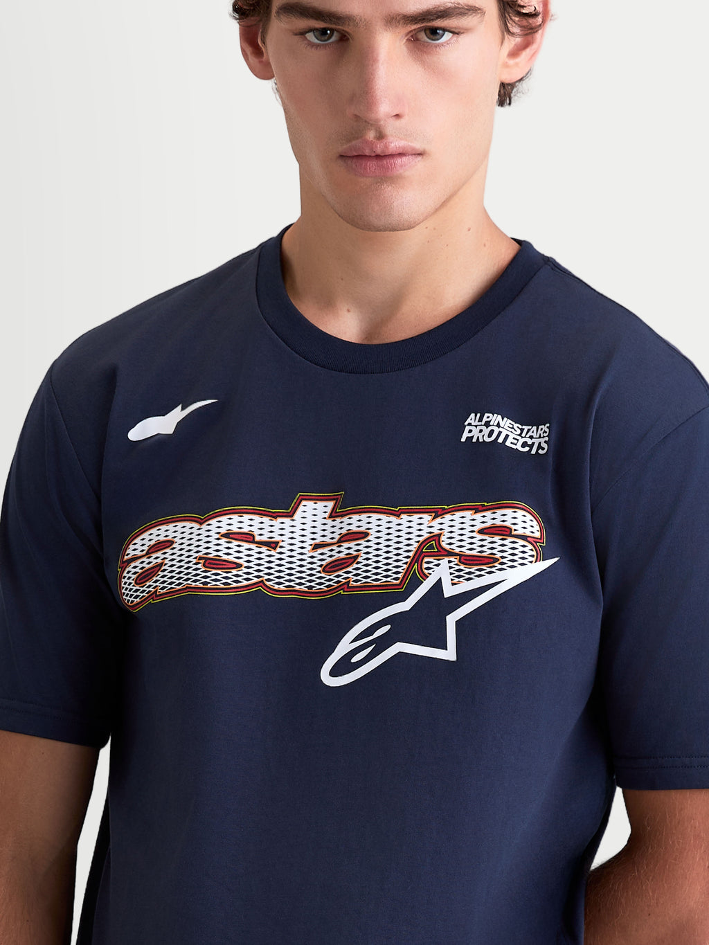 Alpinestars maglietta Cypress CSF, maglietta da uomo a maniche corte sportswear, blu navy e bianca, con grafica Astars sul petto a riempimento mesh, logo e scritta Alpinestars Protects, misto cotone e poliestere, primo piano su modello