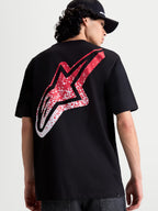 Alpinestars Maglietta Meteor CSF, maglietta a maniche corte nera, vista posteriore su modello con grande logo Astars rosso e bianco sfumato d'ispirazione MX, abbigliamento motorsport casual.