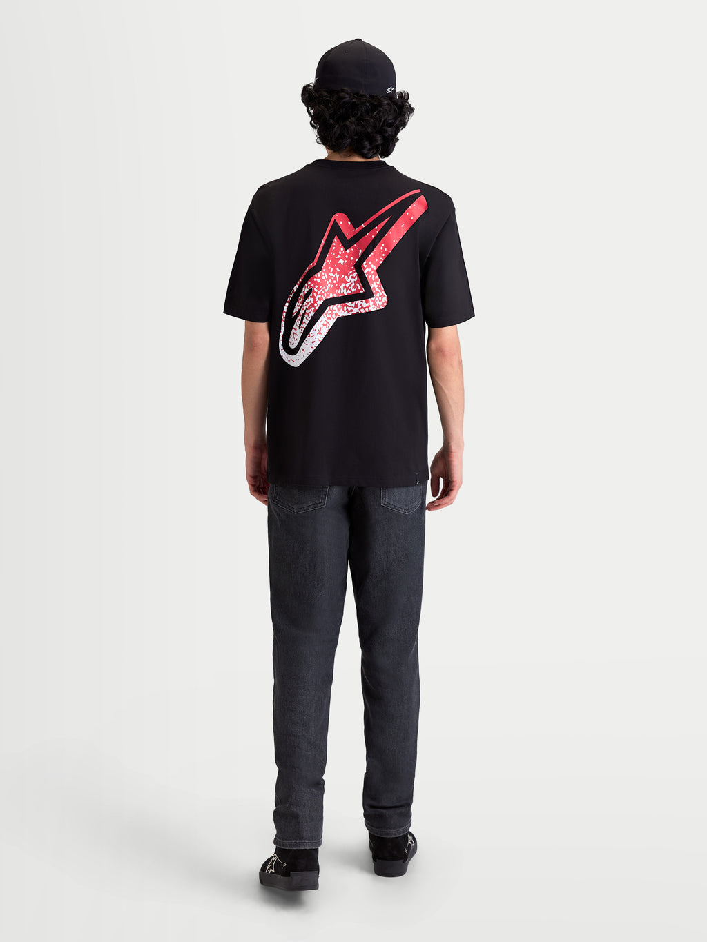 Alpinestars Maglietta Meteor CSF, maglietta a maniche corte nera, vista posteriore su modello con grande logo Astars sulla schiena, grafica sfumata rossa e bianca d'ispirazione MX, stile sportswear casual motorsport.